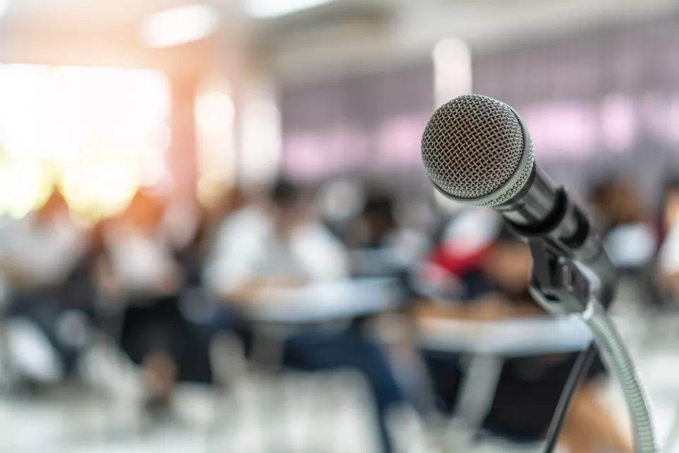 Close-up of microphone on stand with blurred seating in background